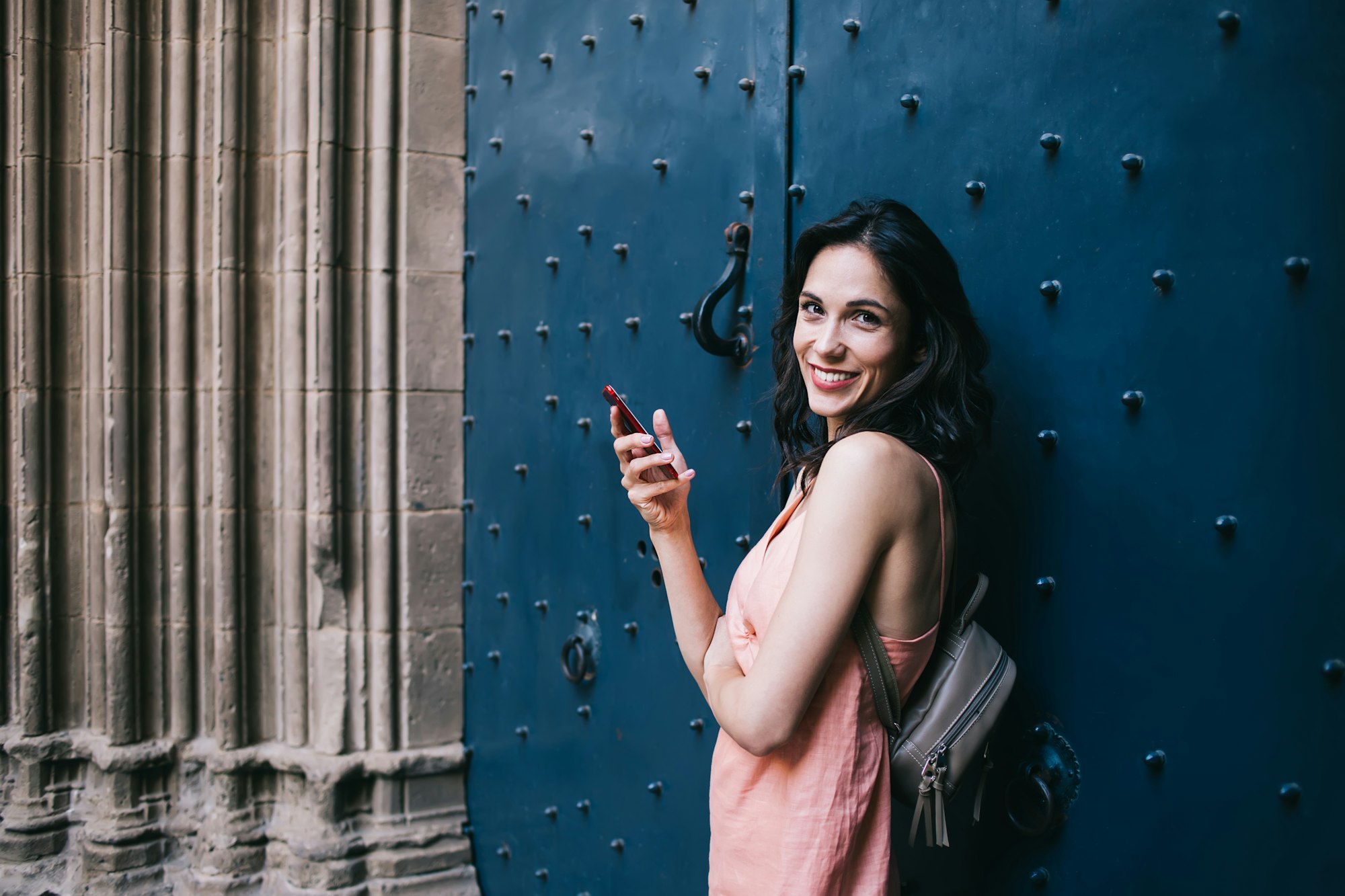 Happy adult tourist using smartphone in old town